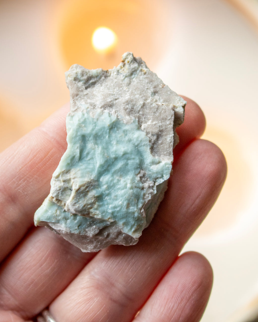 a hand holding a rough blue mineral