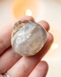 a polished beige agate stone held in the hand