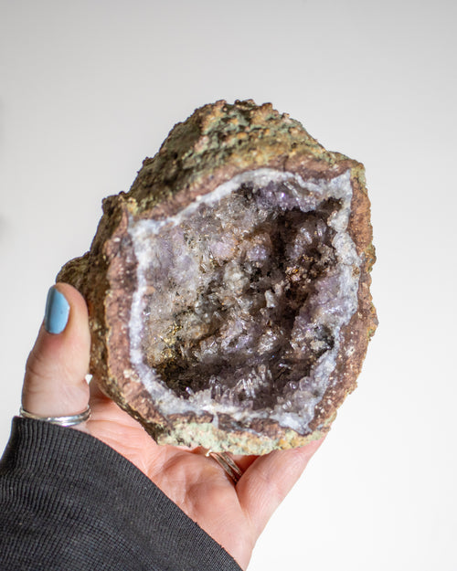 a large geode crystal being held in the hand