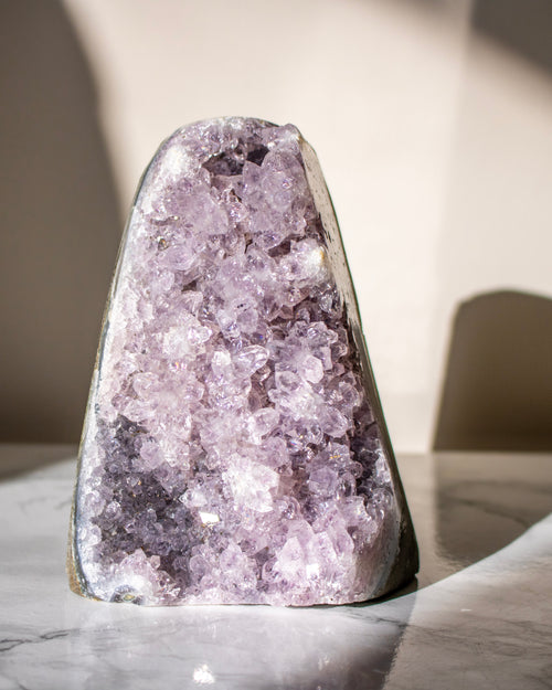 Amethyst crystal on a marble surface with a blurred background