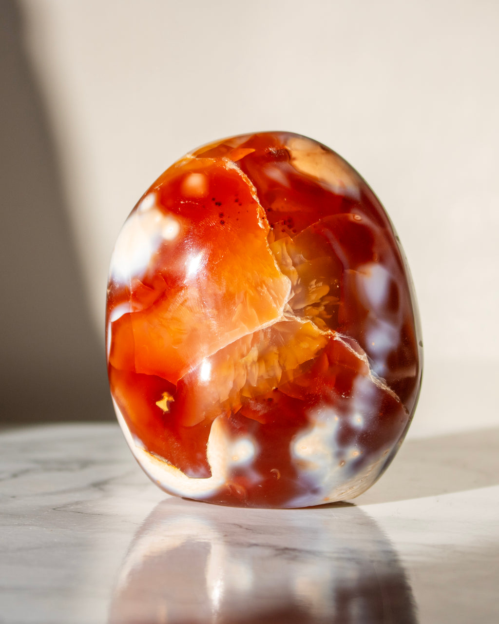 Polished agate stone with orange and white patterns on a marble surface