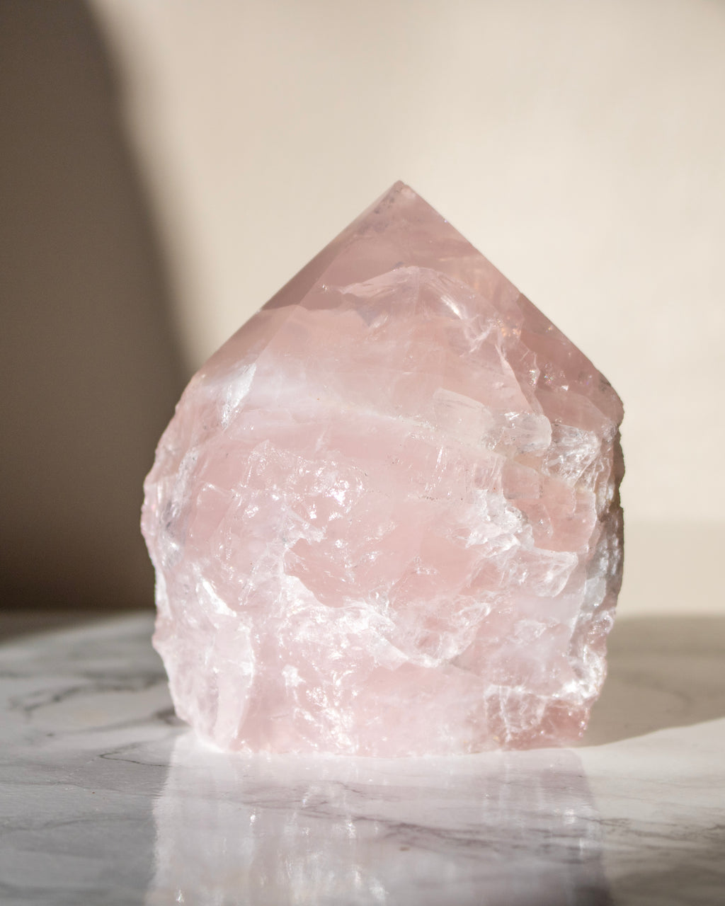 Raw rose quartz crystal on a marble surface