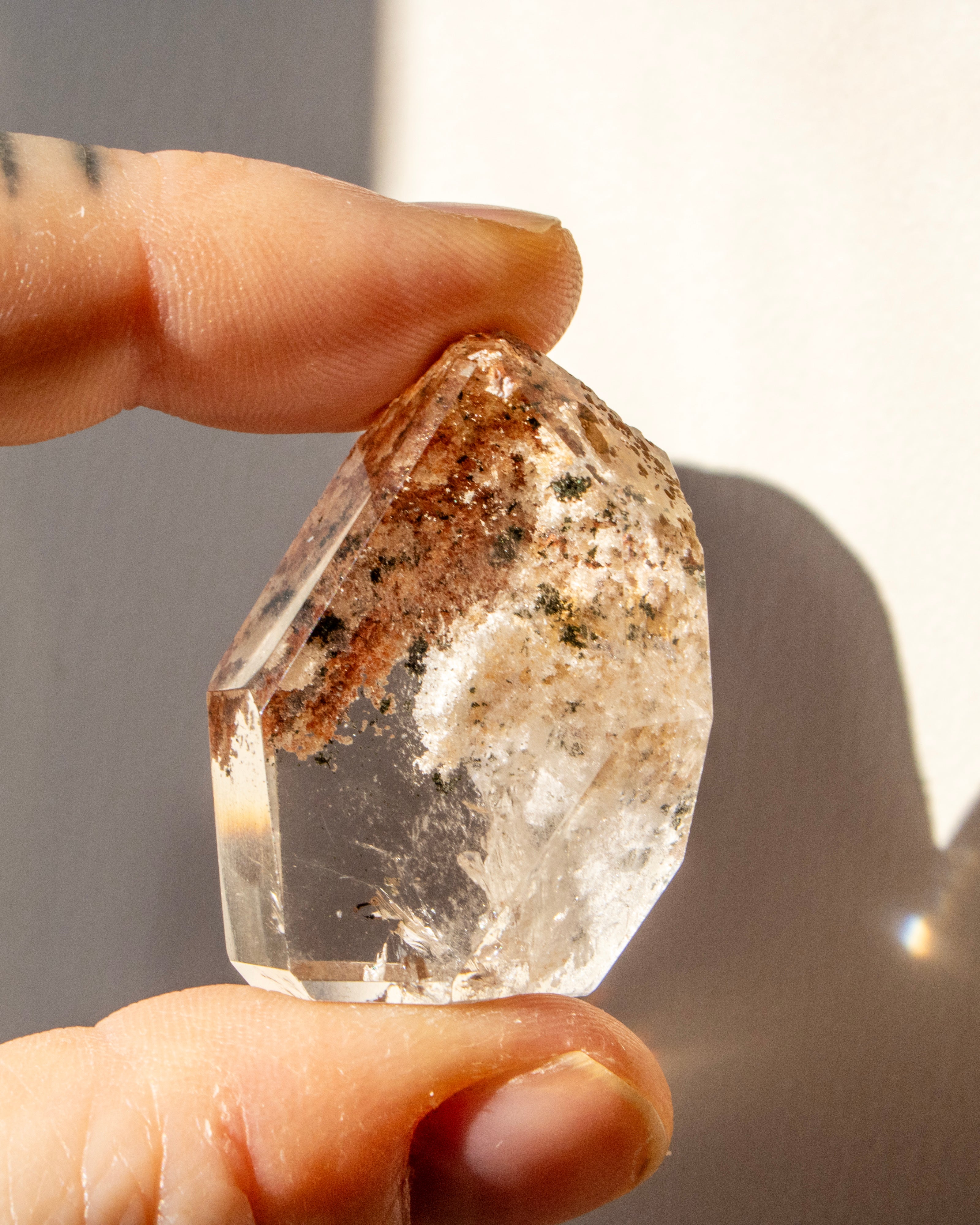 Clear crystal held between fingers with a blurred background