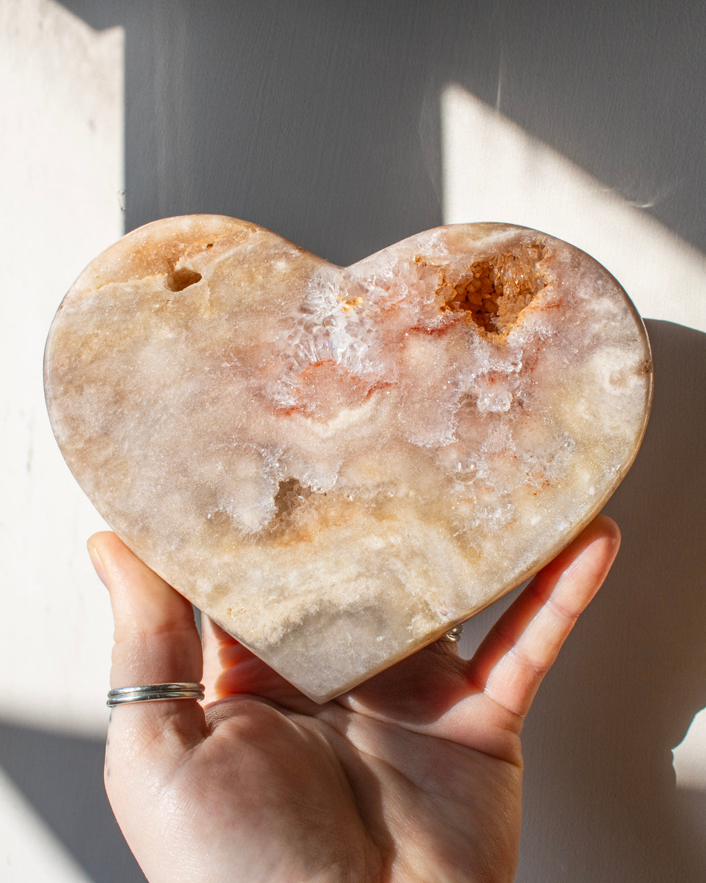 a hand holding a large heart shape pink stone