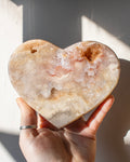 a hand holding a large heart shape pink stone