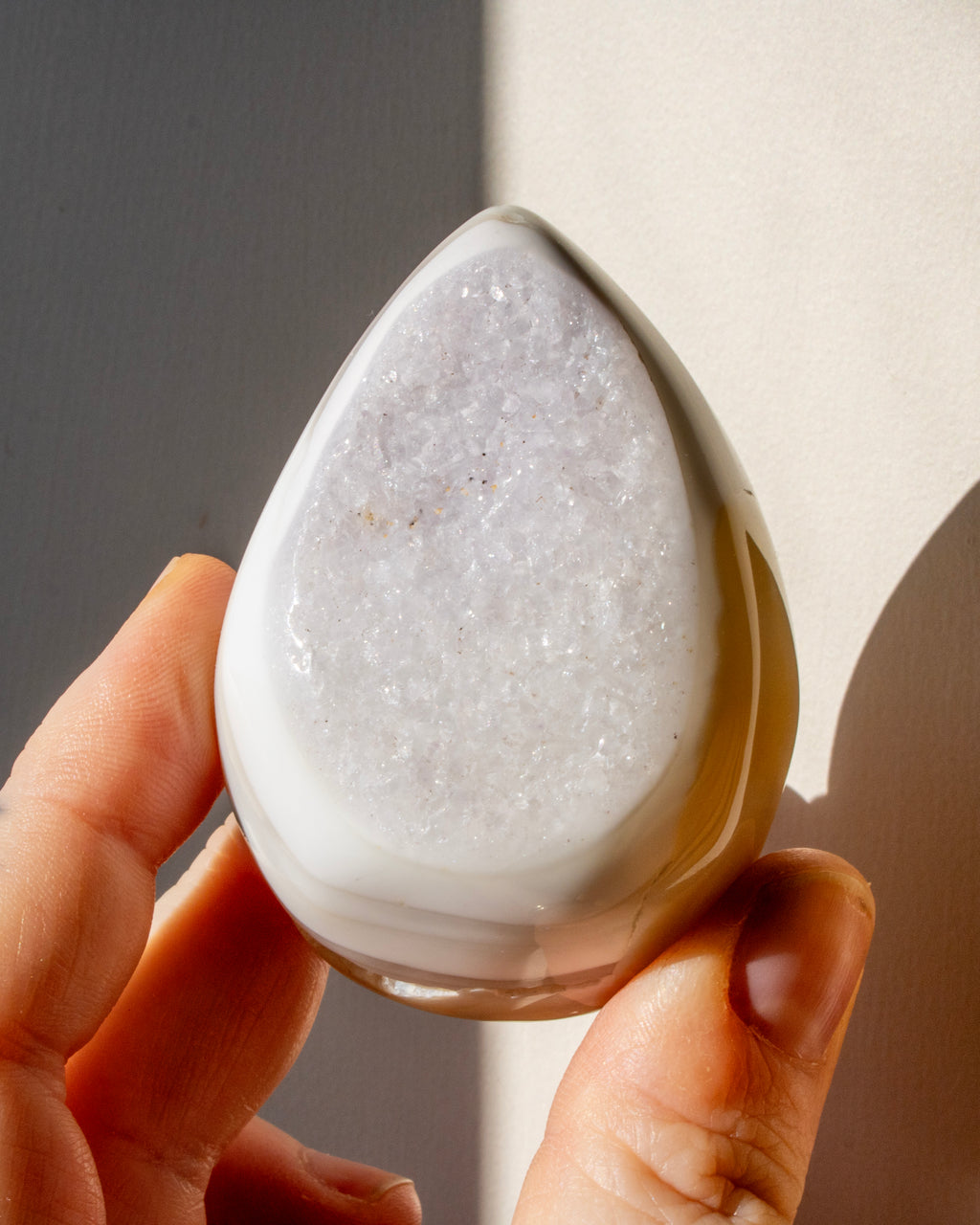 a hand holding a teardrop shaped agate stone