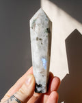 a hand holding a long tapered white stone with a point at one end