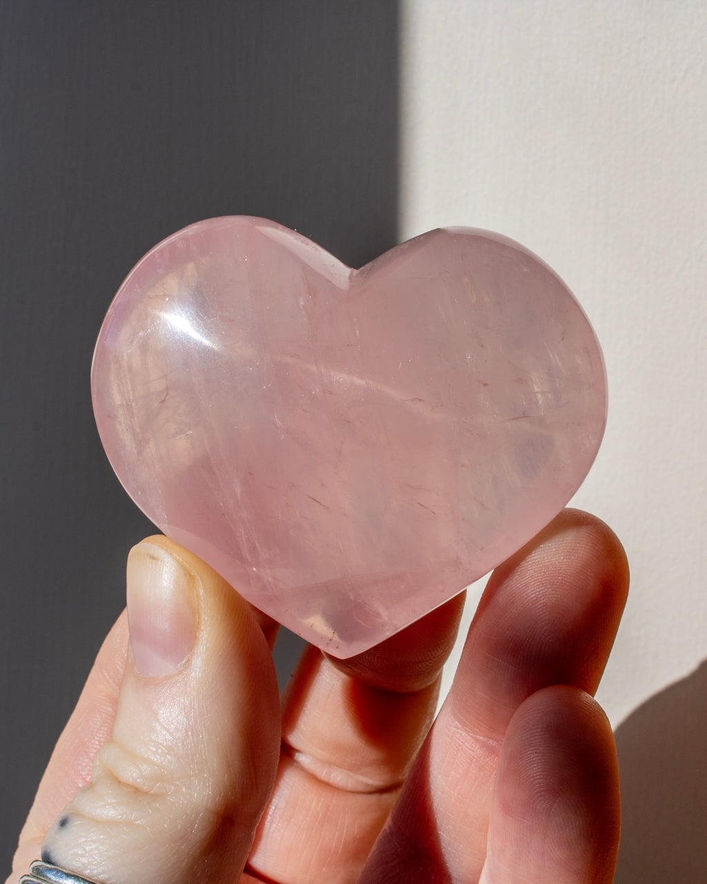 hand holding a pink heart shaped crystal