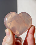 hand holding a pink heart shaped crystal
