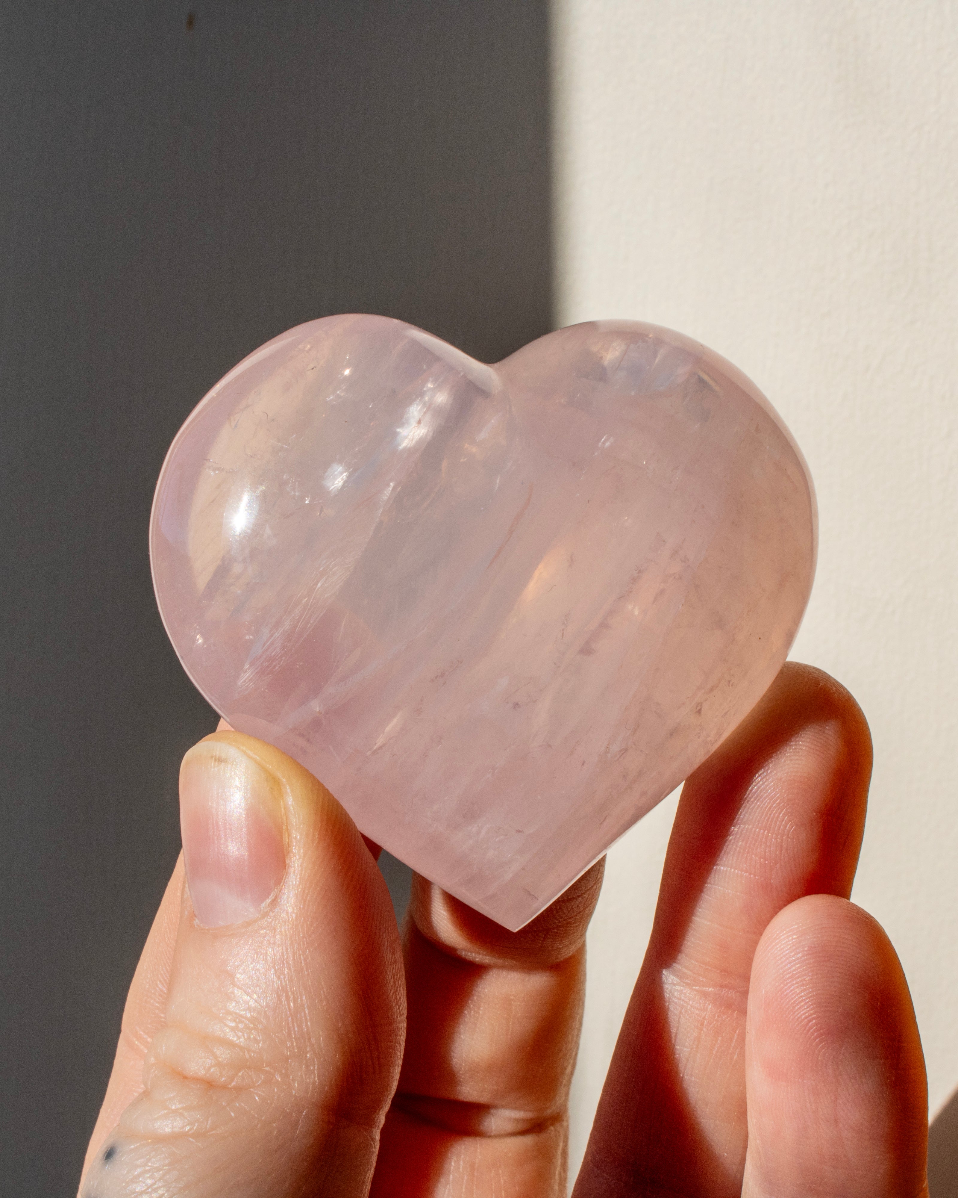 hand holding a pink heart shaped crystal