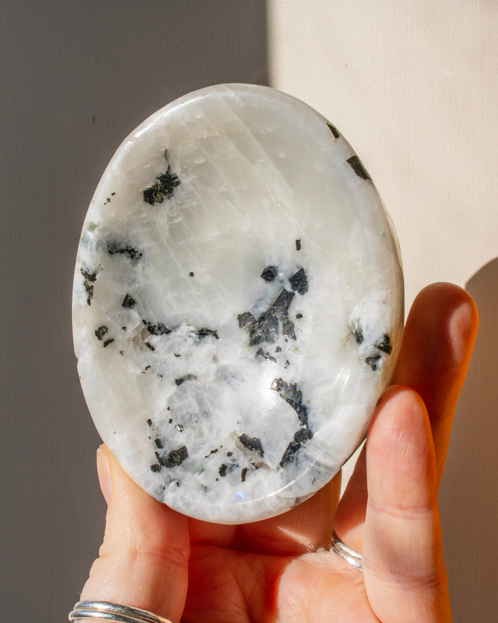 a white oval shape stone being held against a neutral background