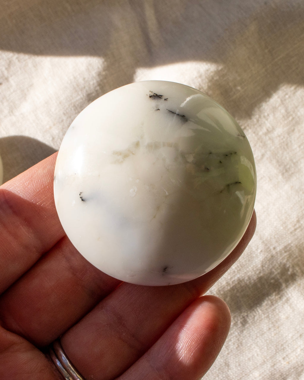 hand holding a round off white stone