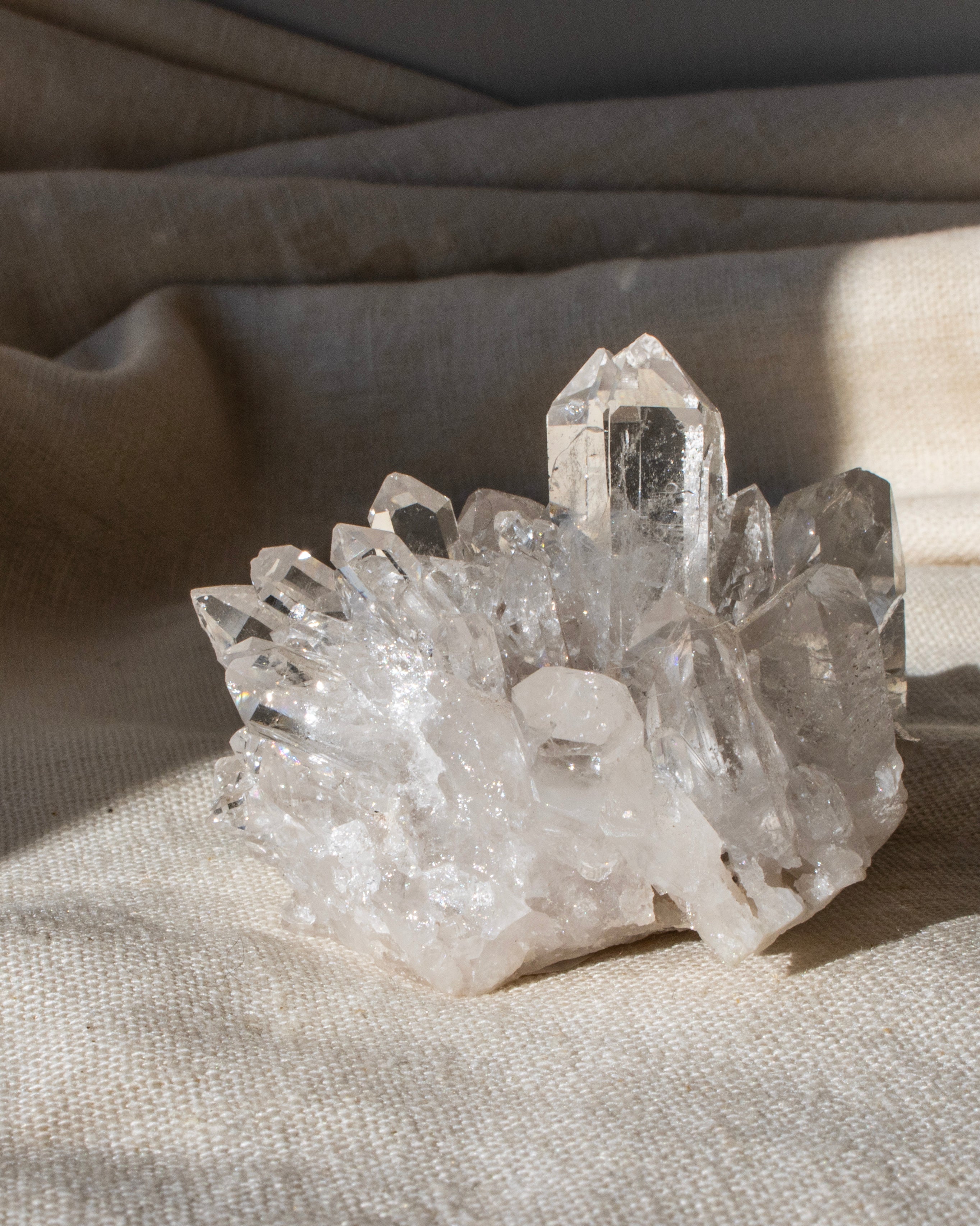 a clear quartz cluster sitting on a textured beige fabric