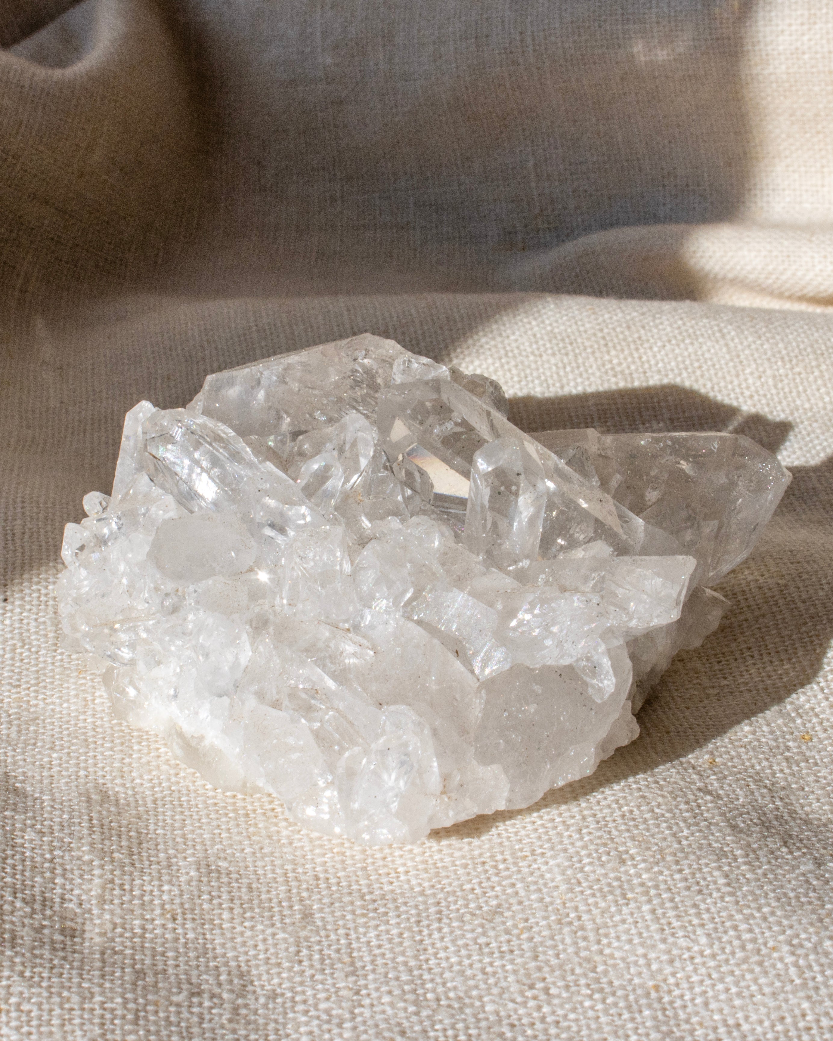 a clear quartz cluster sitting on a textured beige fabric