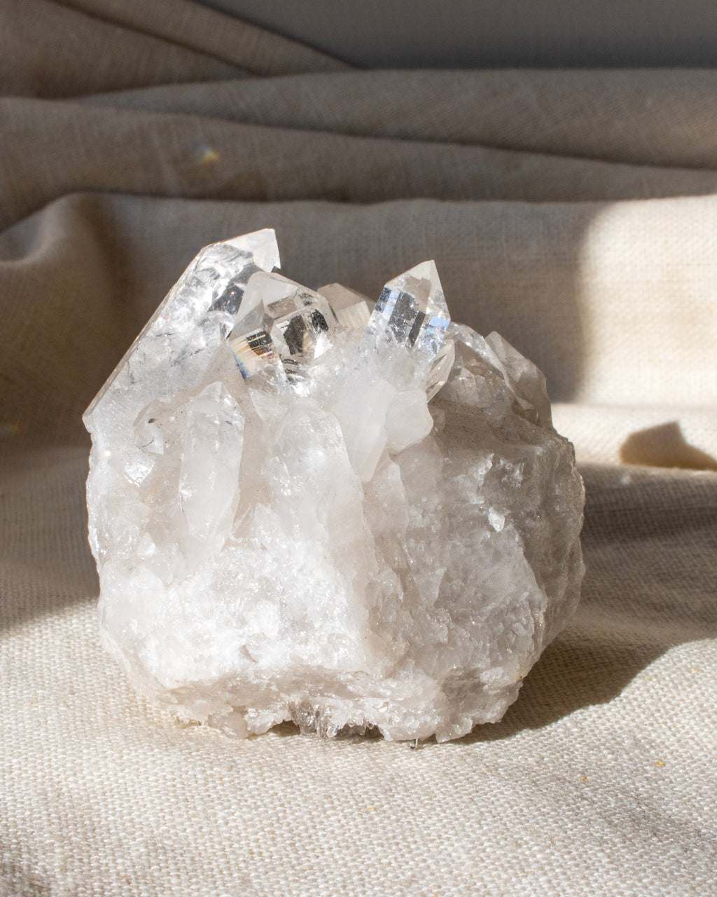 a clear quartz cluster sitting on a textured beige fabric