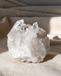 a clear quartz cluster sitting on a textured beige fabric