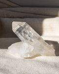 a clear quartz cluster sitting on a textured beige fabric