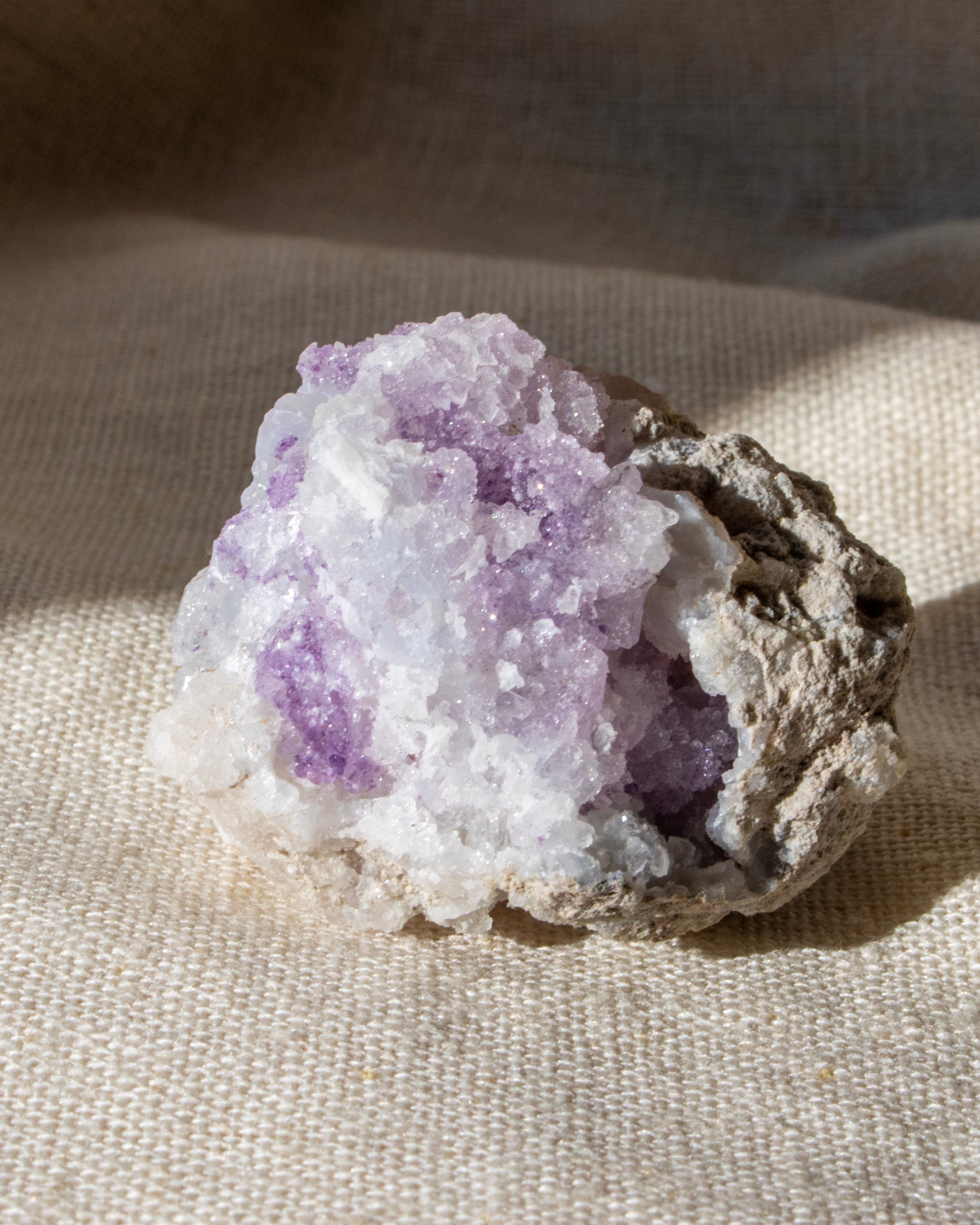a purple geode crystal sitting on a textured beige fabric