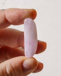 a soft purple crystal being held between fingers