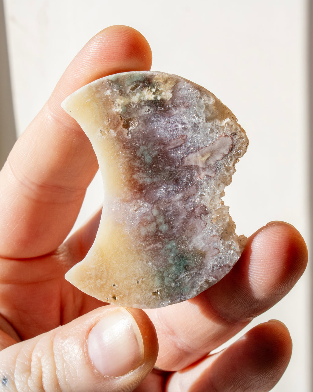 hand holding a multi-coloured moon shaped stone