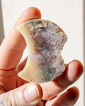 hand holding a multi-coloured moon shaped stone