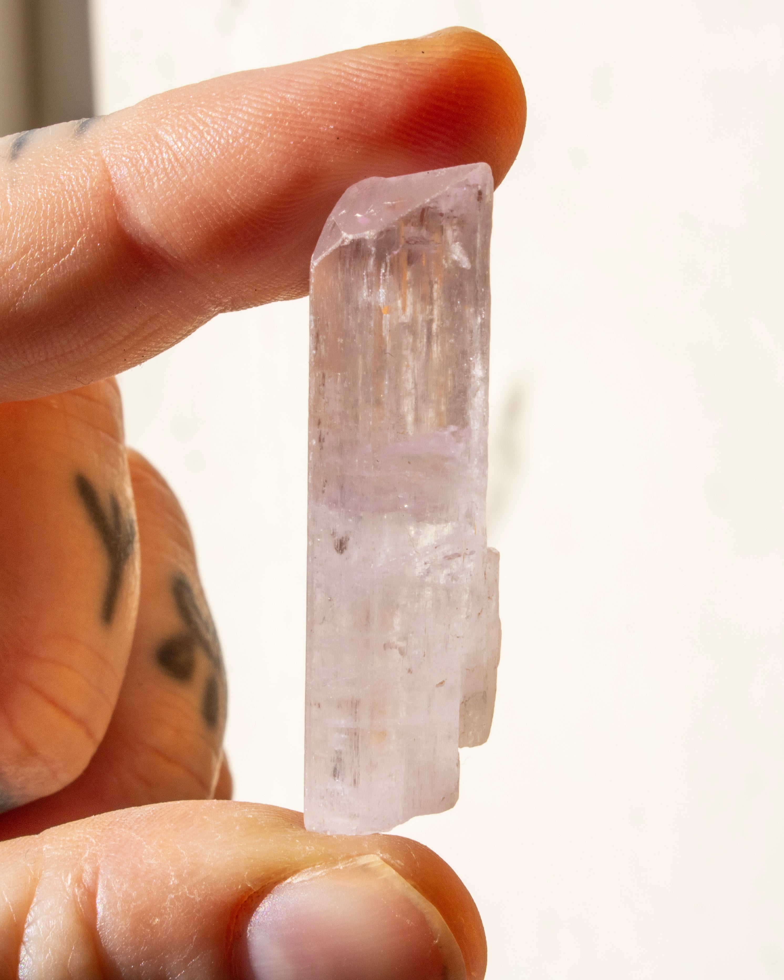 a pale purple crystal being held between fingers
