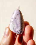 a pale purple stone being held between fingers