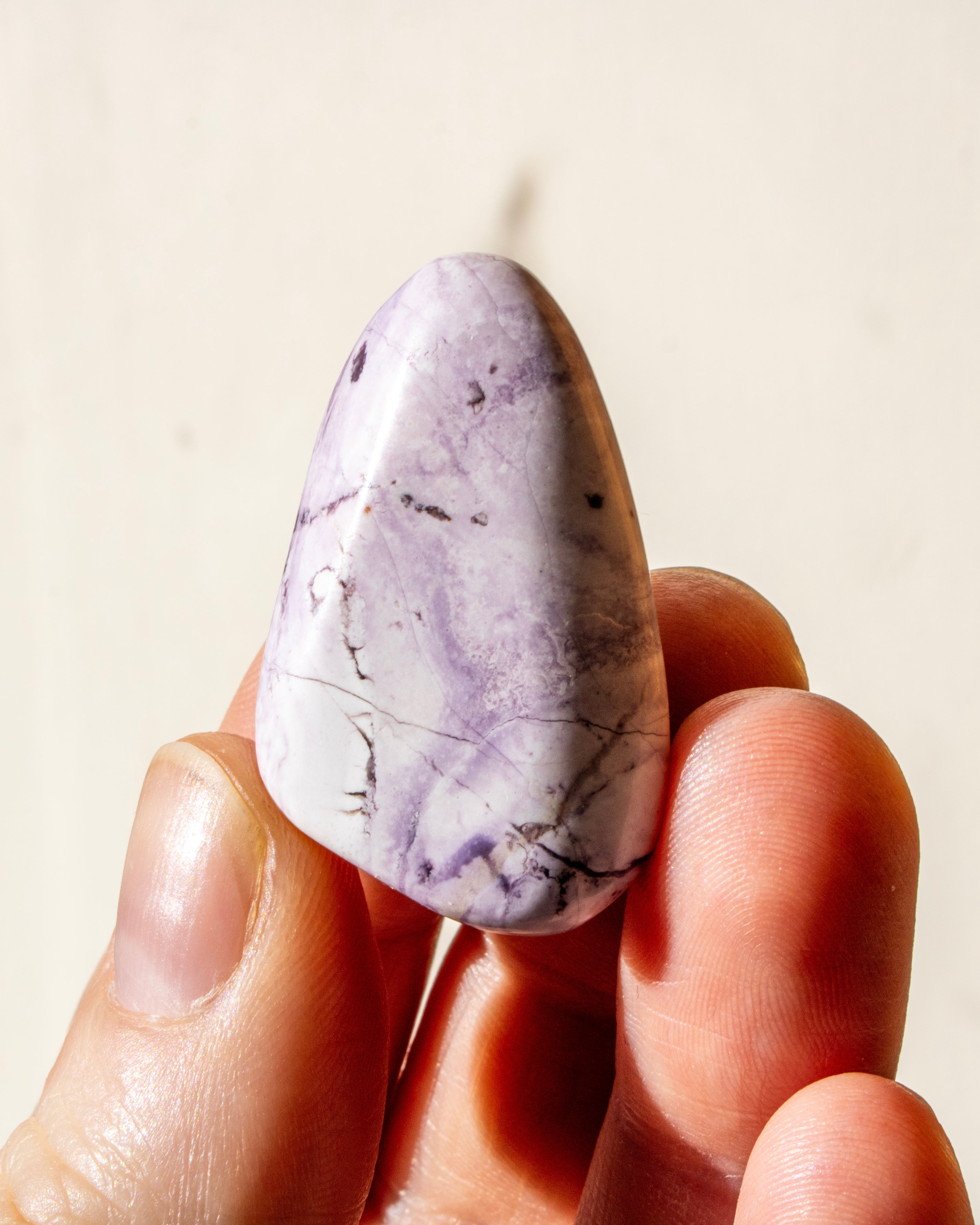 a pale purple stone being held between fingers