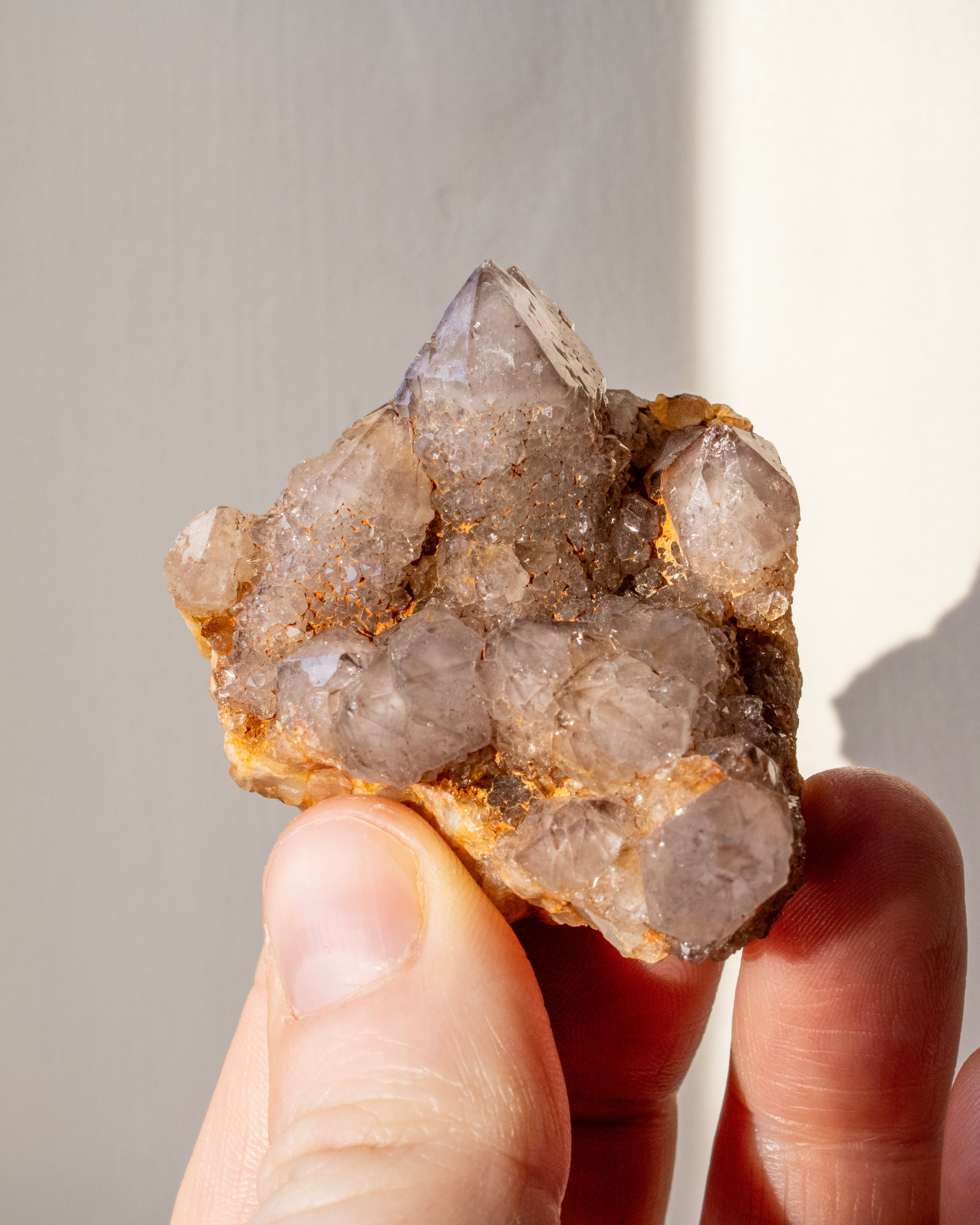 Crystal cluster held in a hand against a neutral background