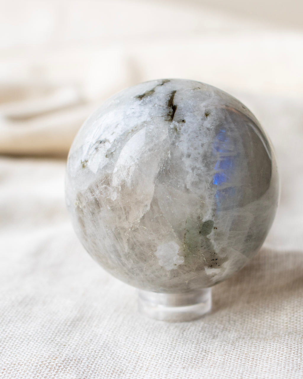 a white and black stone ball with a bright blue patch sitting on a beige linen textured fabric 
