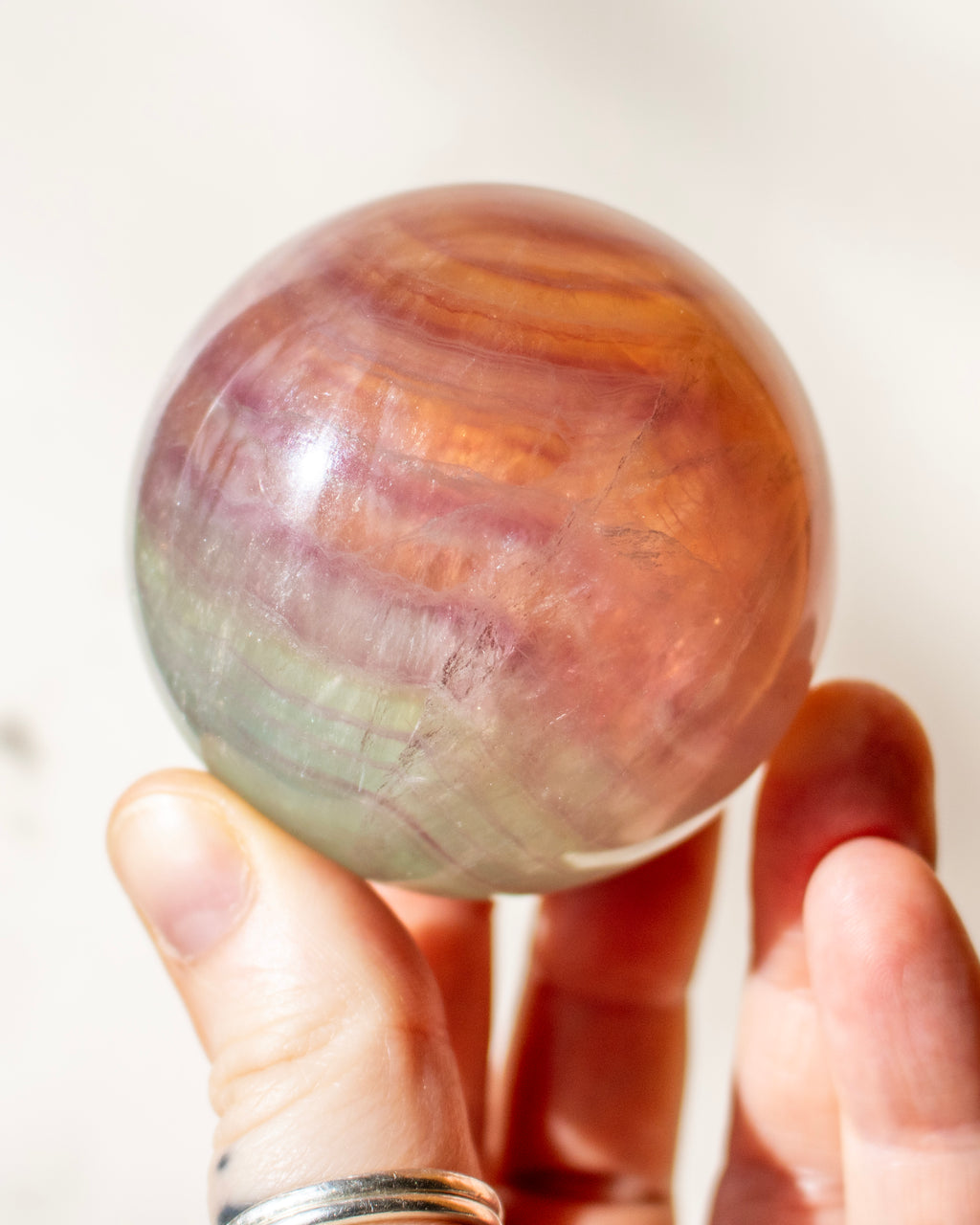 Hand holding a rainbow-colored crystal ball against a white background