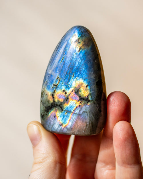 a bright blue labradorite stone being held in a hand