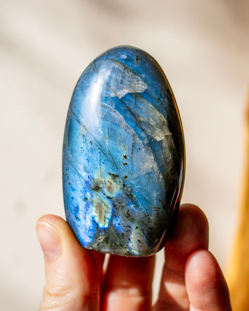 a bright blue labradorite stone being held in a hand