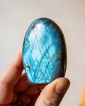 a bright blue labradorite stone being held in a hand