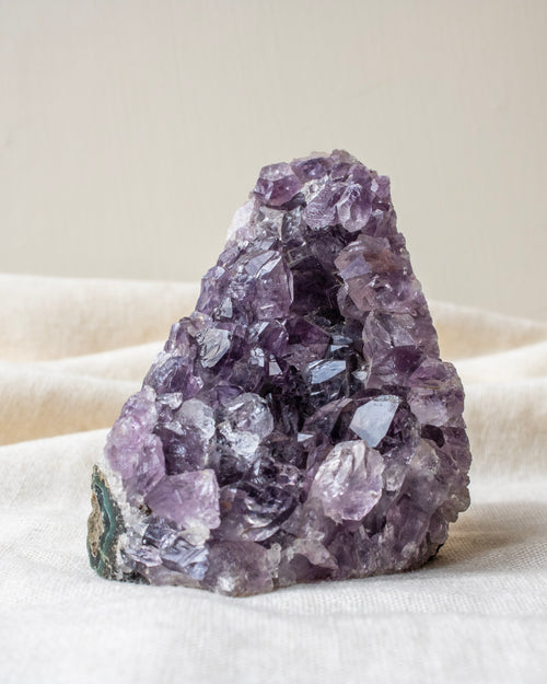Amethyst crystal cluster on a beige fabric background