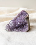 Purple crystal rock on a white fabric surface