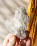 Hand holding a crystal rock against a neutral background