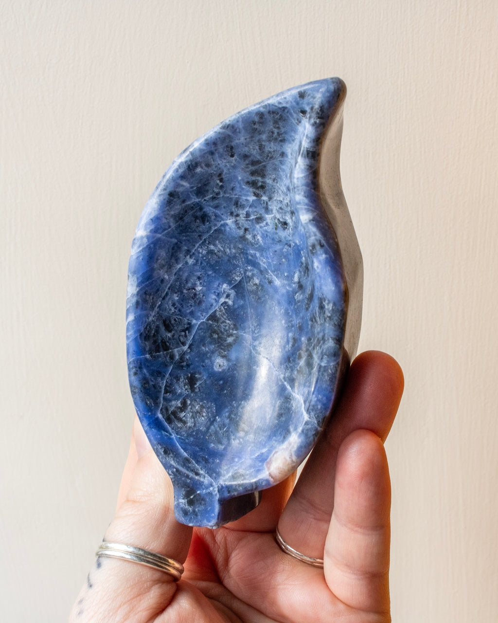 Hand holding a blue stone against a beige background