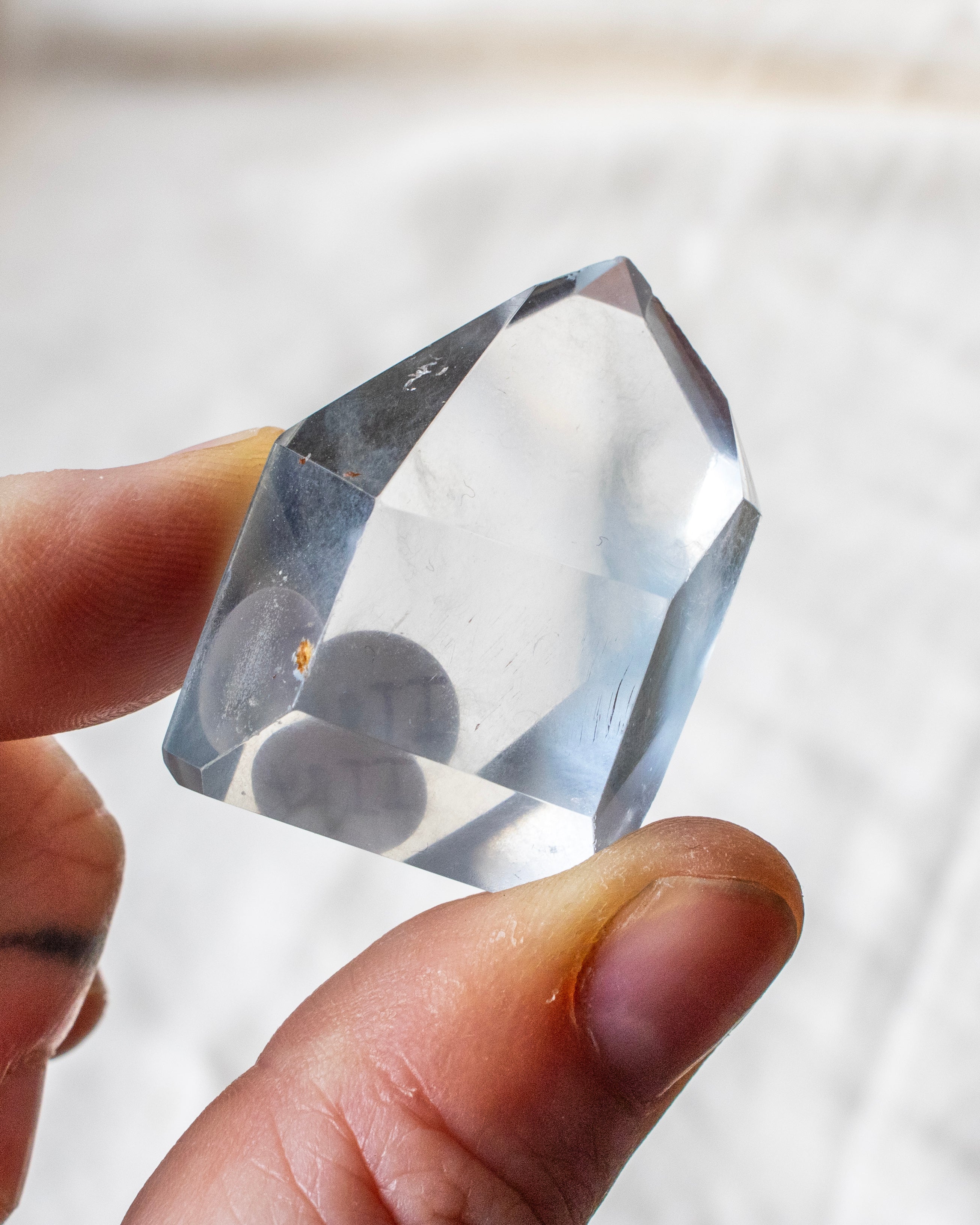 hand holding a clear stone with wispy grey inclusions