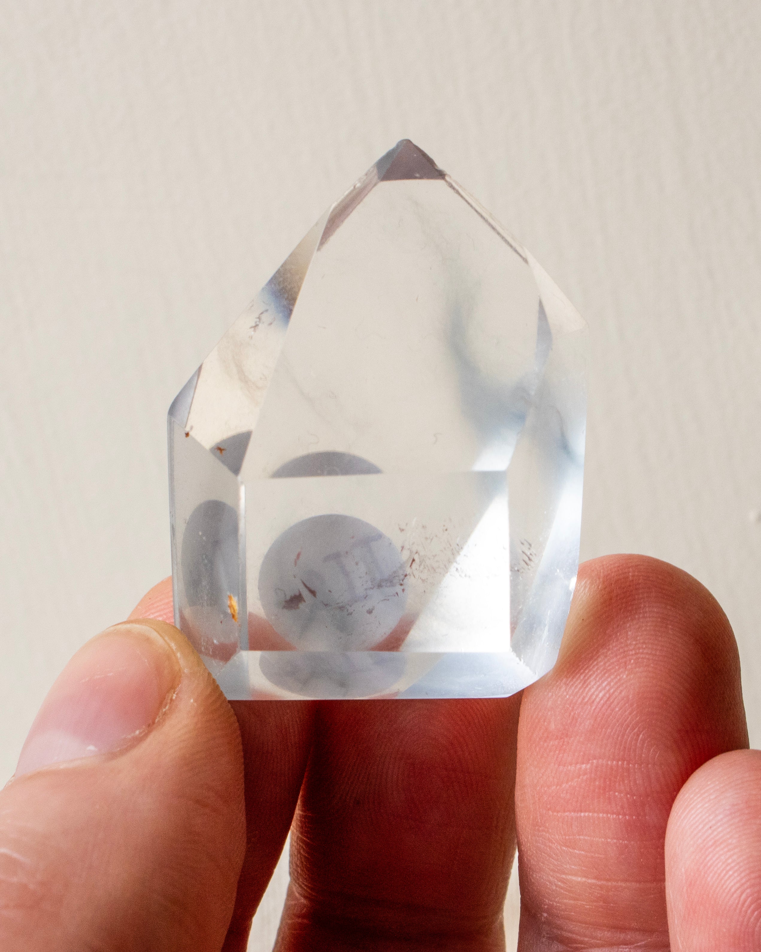 hand holding a clear stone with wispy grey inclusions