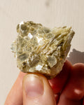 Mineral sample held between fingers against a neutral background