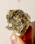 Mineral rock held in a hand against a plain background