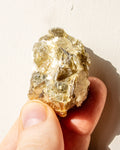 Hand holding a small crystal or mineral against a plain background
