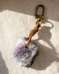Keychain with amethyst crystal and leather strap on a beige fabric background