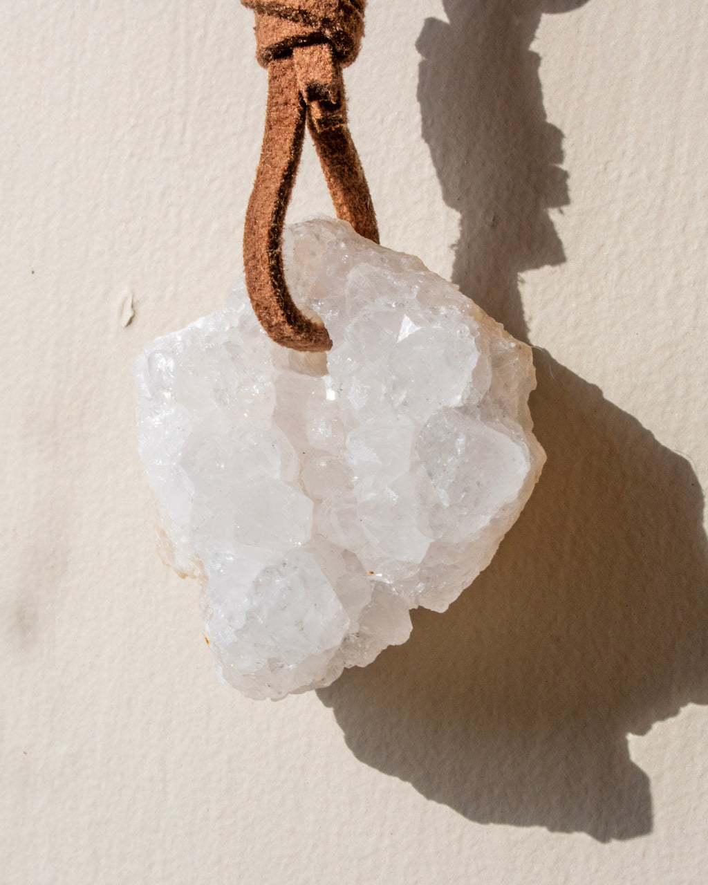 Crystal pendant on a leather cord against a beige background