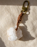 Keychain with a white stone and brown leather strap on a beige fabric background