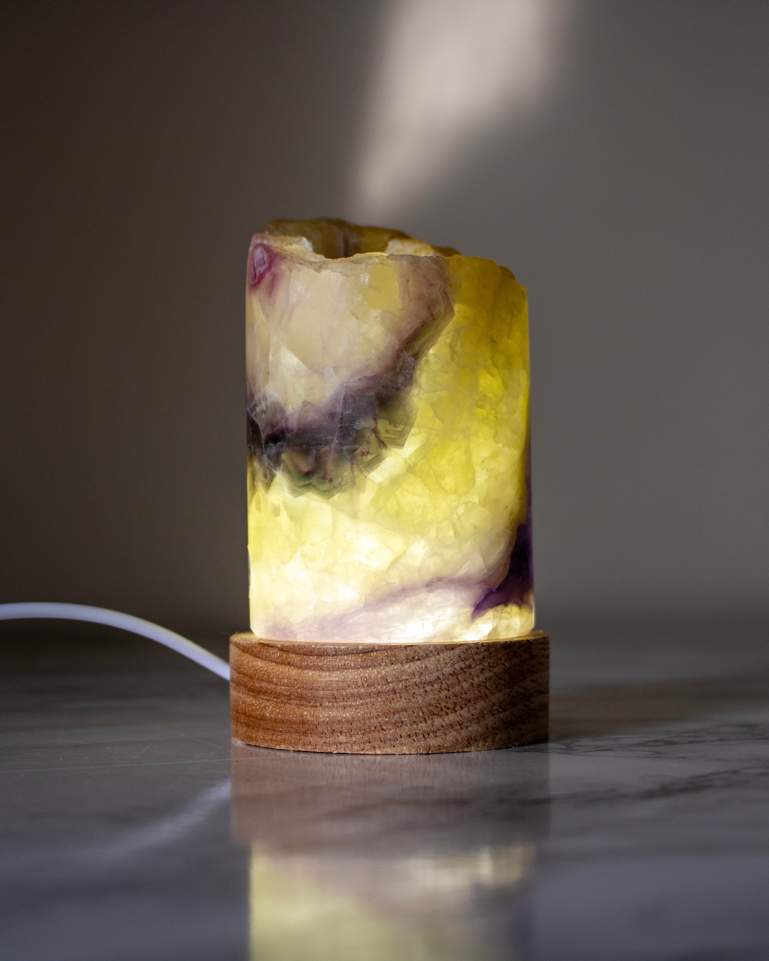 Decorative lamp with a natural stone design on a wooden base against a dark background