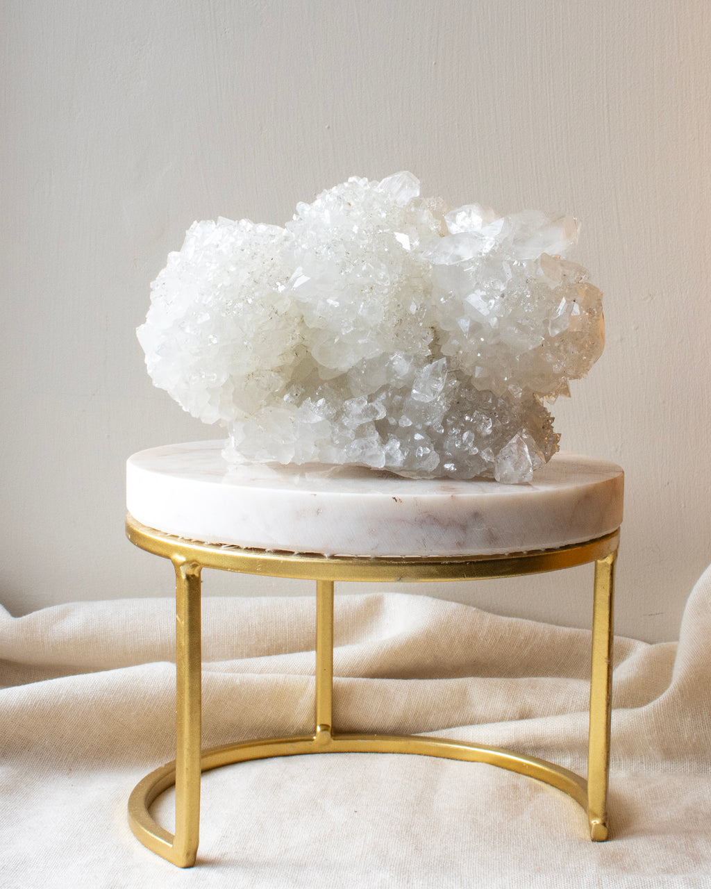 Decorative crystal on a marble and gold stand against a neutral background