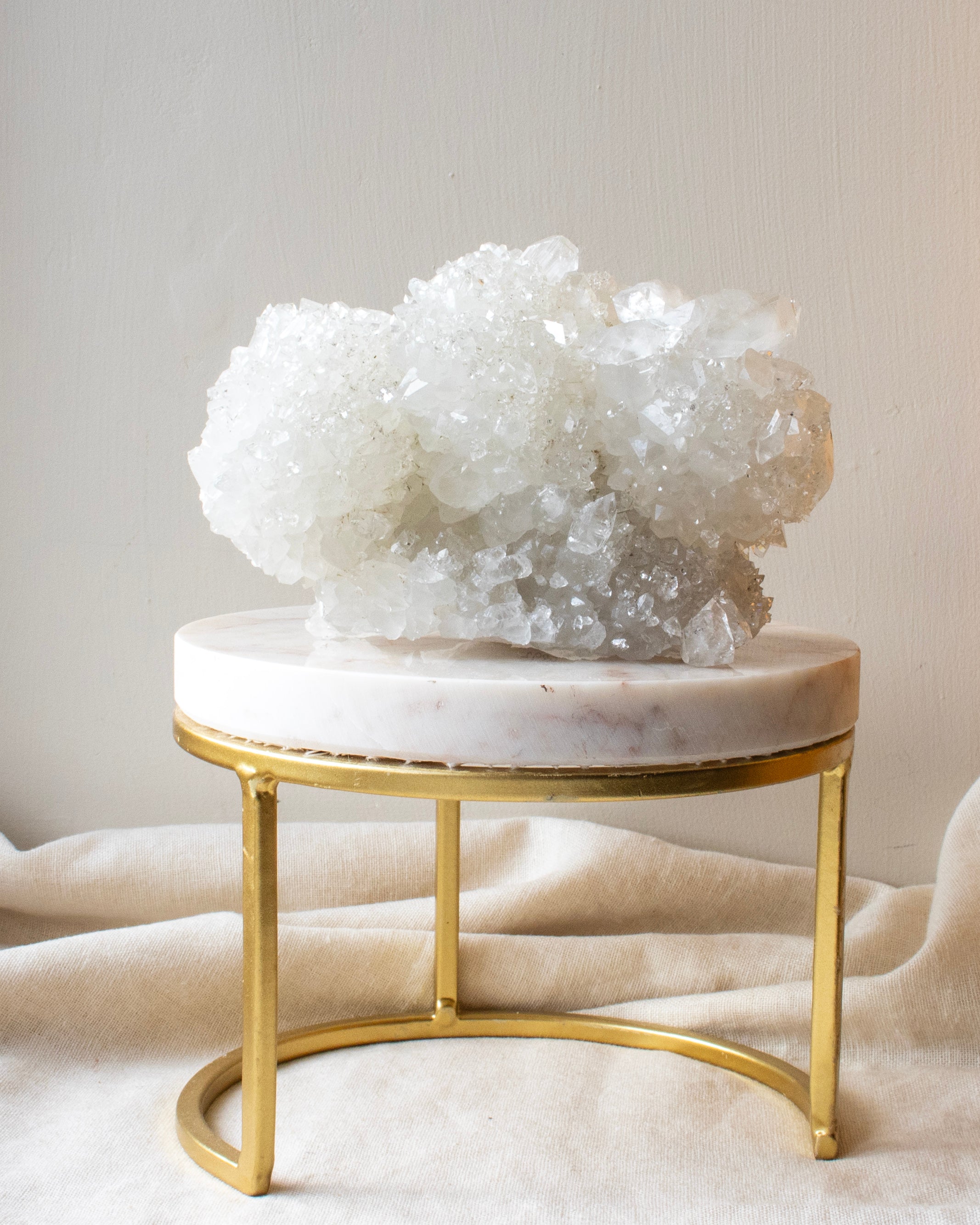 Decorative crystal on a marble and gold stand against a neutral background