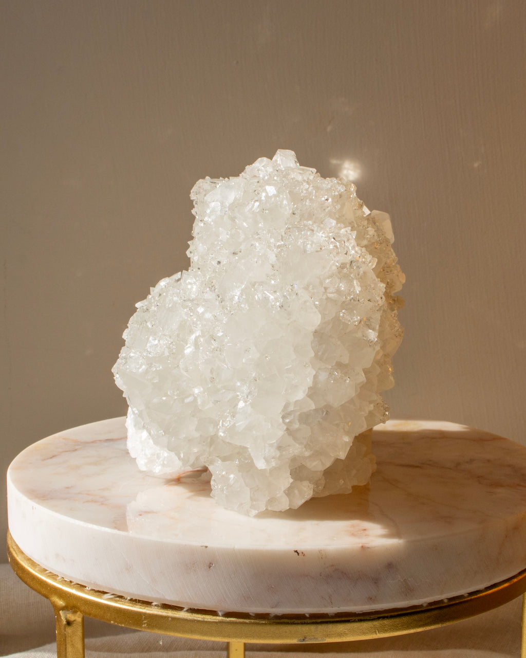 Crystal rock on a marble surface with a gold base against a neutral background